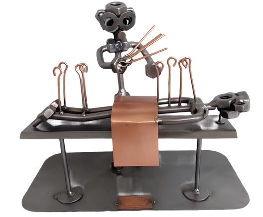 Metallfiguren bei dem ein Mensch eine osteopatische Behandlung hat.